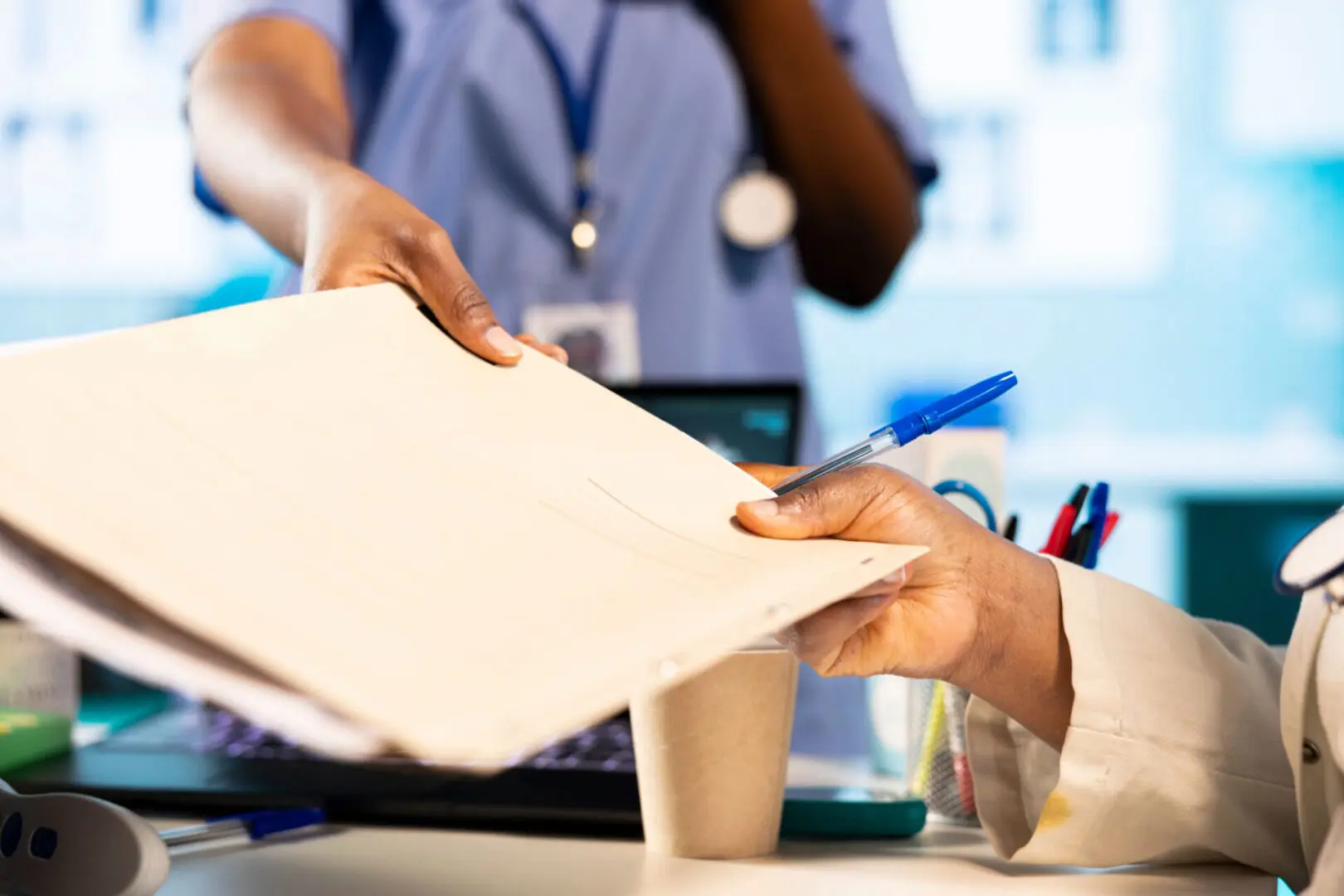 Healthcare professionals exchanging documents at desk.