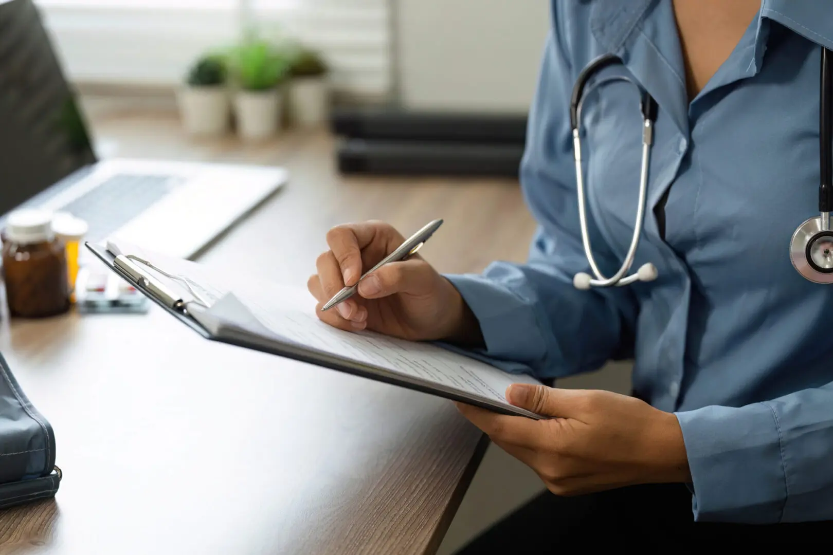 Doctor writing on clipboard at desk.