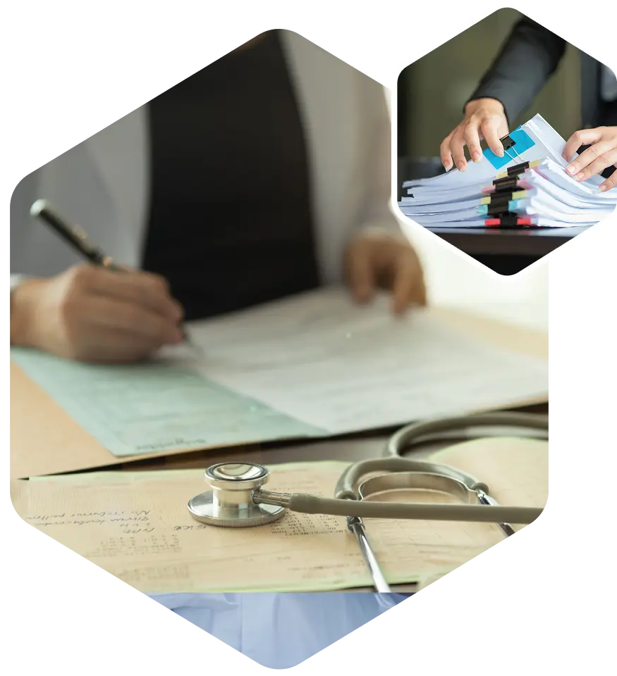 Doctor writing, reviewing documents with stethoscope nearby.