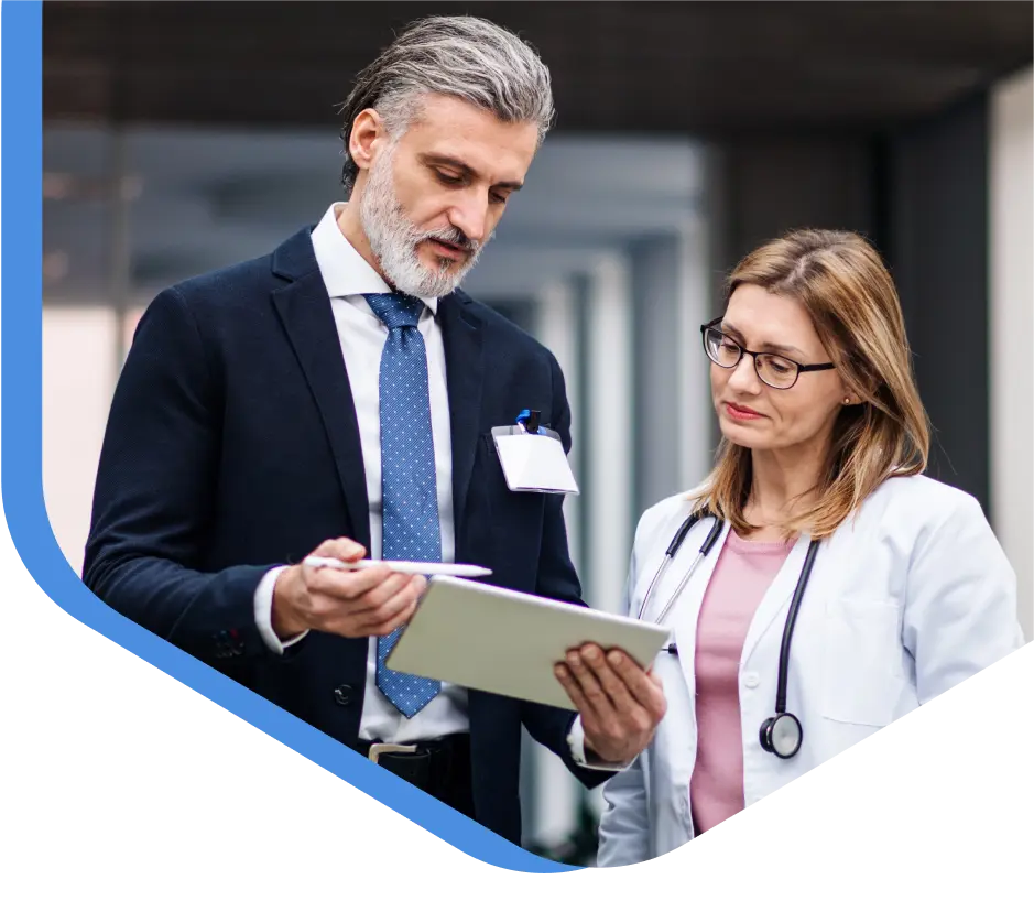 Two doctors reviewing patient information on a digital tablet.